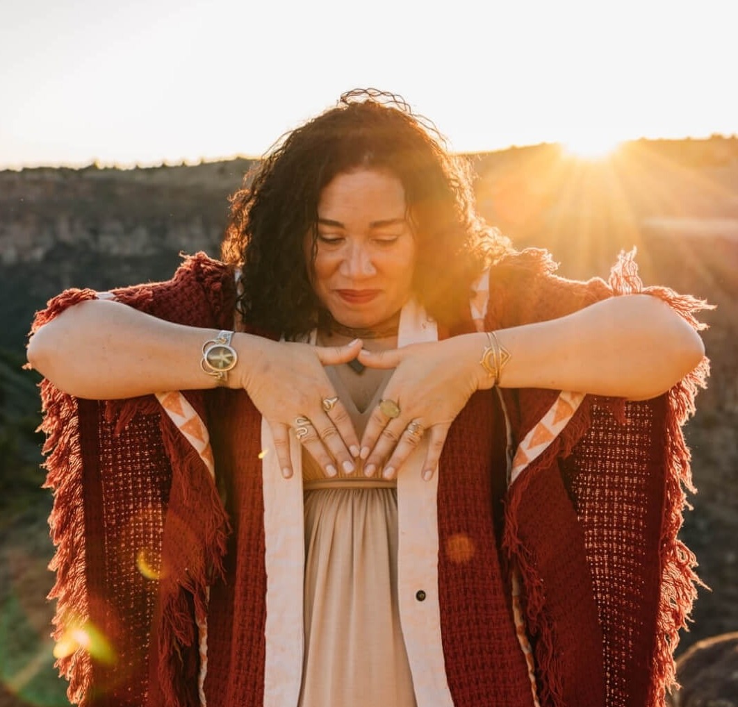 Elisha with hands forming a triangle at her chest. The tip of her fingers are forming the top point of the triangle and pointing downwards
