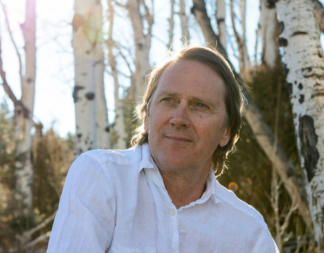 A man sitting in a forest with the sun behind him